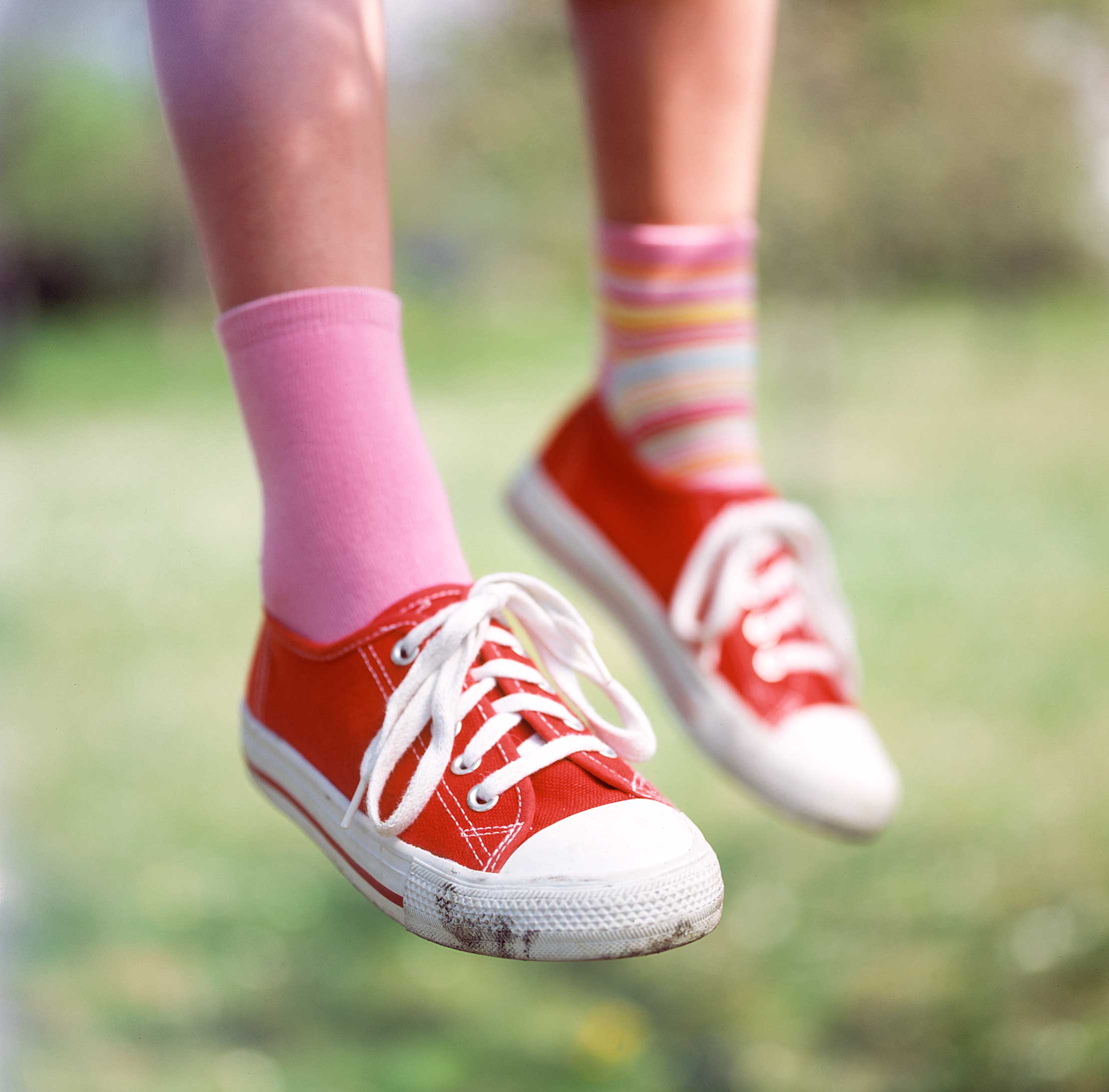 Kind trägt rote Stoffturnschuhe und verschiedene bunte Socken